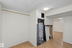 Utility area featuring a water heater, built-in storage, and wood-finish flooring - 