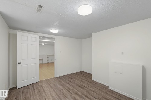Open interior space featuring wood-finish flooring, white walls, and a recessed ceiling vent - 11147 78 Avenue Nw, Edmonton, AB 