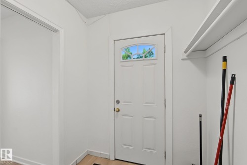 Entryway featuring a white paneled door with an arched glass insert, light wood-finish flooring, and white baseboards - 11147 78 Avenue Nw, Edmonton, AB 