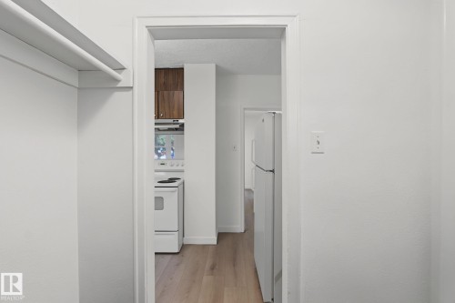 Hallway entrance featuring a bright white refrigerator and light wood-finish flooring - 11147 78 Avenue Nw, Edmonton, AB 