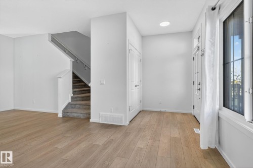 Entryway featuring wood-finish flooring, white walls, and a front door with glass panels - 264 Orchards Boulevard Sw, Edmonton, AB - Indoor Photo Showing Other Room