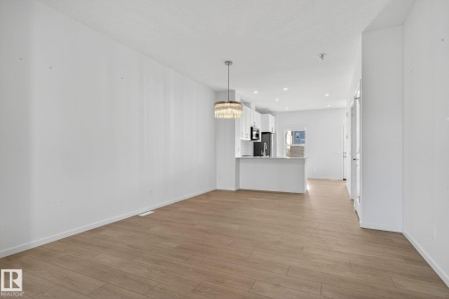 Open-concept living space featuring wood-finish flooring, recessed lighting, and a contemporary chandelier - 264 Orchards Boulevard Sw, Edmonton, AB - Indoor