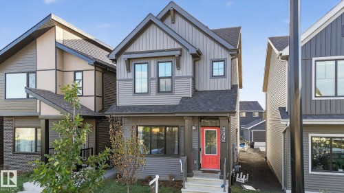 Contemporary residential exterior with multiple siding textures, a prominent red front door, dark-framed windows, a covered front porch, and a clear house number - 264 Orchards Boulevard Sw, Edmonton, AB - Outdoor