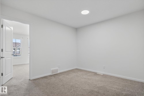 Neutral-toned carpeting throughout this space with a single recessed ceiling light fixture - 264 Orchards Boulevard Sw, Edmonton, AB - Indoor Photo Showing Other Room