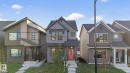Contemporary gray siding residence featuring a bold red entry door, a covered front porch, and black-framed windows - 264 Orchards Boulevard Sw, Edmonton, AB  - Outdoor With Facade 