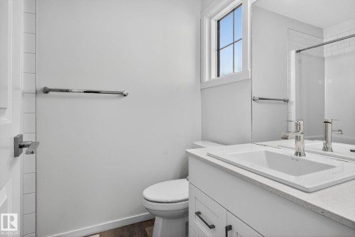 Bathroom featuring a white vanity with an integrated sink, polished chrome faucet, square-edged countertop, and dark cabinet hardware - 264 Orchards Boulevard Sw, Edmonton, AB - Indoor Photo Showing Bathroom