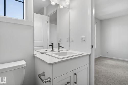 Modern bathroom vanity with integrated sink, stone-finish countertop, and chrome fixtures - 264 Orchards Boulevard Sw, Edmonton, AB - Indoor Photo Showing Bathroom