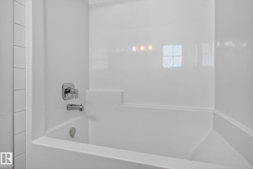White bathtub with integrated surround, chrome fixtures, and a subway tile wall - 264 Orchards Boulevard Sw, Edmonton, AB - Indoor Photo Showing Bathroom