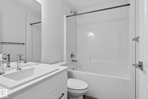 Bathroom featuring a white bathtub with subway tile surround, chrome fixtures, a modern vanity with integrated sink, and a large wall-mounted mirror - 264 Orchards Boulevard Sw, Edmonton, AB - Indoor Photo Showing Bathroom