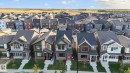Aerial perspective showcasing multiple homes with varied architectural styles and exterior finishes, featuring a backdrop of open fields - 264 Orchards Boulevard Sw, Edmonton, AB  - Outdoor With Facade 