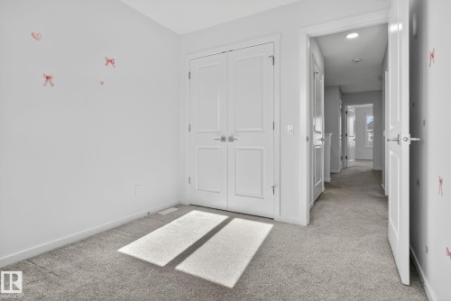 Carpeted room featuring white trim, bi-fold closet doors, and recessed lighting in the hallway - 264 Orchards Boulevard Sw, Edmonton, AB - Indoor Photo Showing Other Room