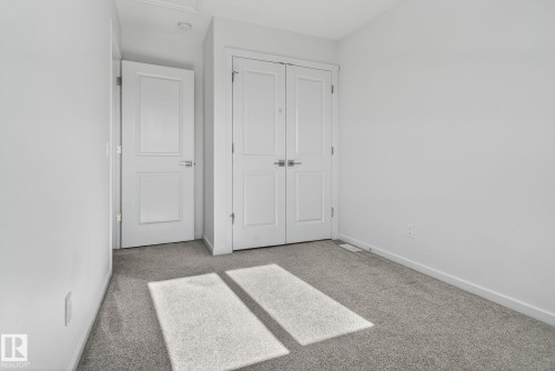 Clean, neutral-toned room featuring light gray carpeting, crisp white walls, and bright white trim - 264 Orchards Boulevard Sw, Edmonton, AB - Indoor Photo Showing Other Room