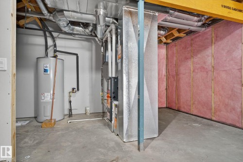 Utility area featuring a water heater, furnace system, and exposed ductwork - 264 Orchards Boulevard Sw, Edmonton, AB - Indoor Photo Showing Basement