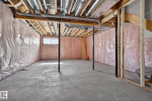 Unfinished basement with concrete flooring, exposed ceiling joists, visible insulation, and a single window - 264 Orchards Boulevard Sw, Edmonton, AB - Indoor Photo Showing Basement