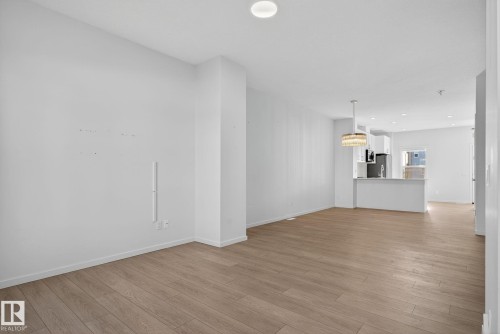 Spacious open-concept room featuring wood-finish flooring and recessed lighting - 264 Orchards Boulevard Sw, Edmonton, AB - Indoor