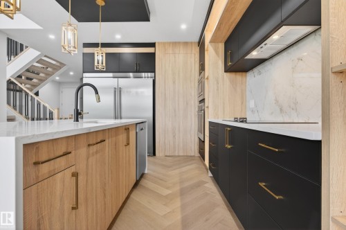 Contemporary kitchen with a white countertop island, integrated stainless steel appliances, and herringbone pattern wood-finish flooring - 431 172 Avenue, Edmonton, AB - Indoor Photo Showing Kitchen