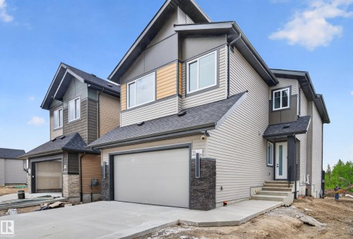 Contemporary multi-textured exterior featuring light gray siding, dark gray accents, and a front-facing garage with a concrete driveway - 431 172 Avenue, Edmonton, AB - Outdoor