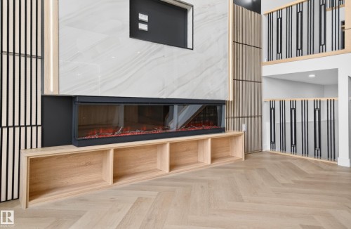 Modern fireplace feature wall with a linear electric fireplace, built-in open shelving, and light wood-finish slat detailing - 431 172 Avenue, Edmonton, AB - Indoor Photo Showing Other Room