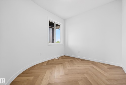 Bright interior space featuring light wood-finish flooring in a herringbone pattern and a white window frame - 431 172 Avenue, Edmonton, AB - Indoor Photo Showing Other Room