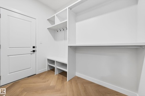 Built-in mudroom organization featuring bench seating, open shelving, integrated coat hooks, and a wardrobe rod - 431 172 Avenue, Edmonton, AB - Indoor With Storage