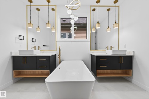 Freestanding soaking tub with floor-mounted fixture, flanked by dual floating vanities featuring black cabinetry, light wood-finish open shelving, and white vessel sinks - 431 172 Avenue, Edmonton, AB - Indoor Photo Showing Bathroom