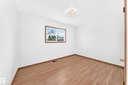 Bright interior space featuring wood-finish flooring, white walls, and a ceiling-mounted light fixture - 10819 137 Avenue Nw, Edmonton, AB - Indoor Photo Showing Other Room