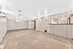 Spacious lower level featuring wood-panel walls, drop ceiling, and concrete flooring - 