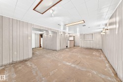 Spacious room with light-toned paneled walls, a white panel ceiling, and concrete flooring - 