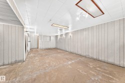 Spacious room featuring light-colored vertical paneling, a white paneled ceiling, and concrete flooring - 