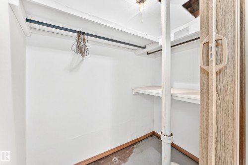 Storage space featuring a bi-fold door with a light wood-grain finish, white walls, and a built-in shelf - 10819 137 Avenue Nw, Edmonton, AB - Indoor With Storage