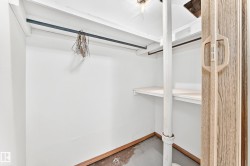 Storage space featuring a bi-fold door with a light wood-grain finish, white walls, and a built-in shelf - 