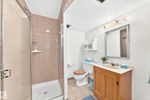Bathroom featuring a shower stall with pink tile surround, a built-in shower caddy, and a glass enclosure - 10819 137 Avenue Nw, Edmonton, AB - Indoor Photo Showing Bathroom