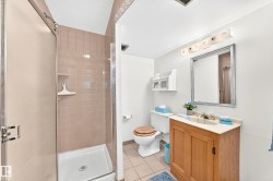 Bathroom featuring a shower stall with pink tile surround, a built-in shower caddy, and a glass enclosure - 