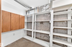 Utility space featuring wall-mounted wooden cabinetry, extensive built-in shelving, concrete walls, a window, and exposed ductwork - 