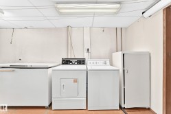 Dedicated laundry area featuring a drop ceiling with fluorescent lighting, durable flooring, and ample space for appliances - 