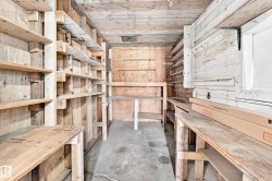 Utility space featuring extensive wood shelving, a concrete floor, and a wood-paneled ceiling - 
