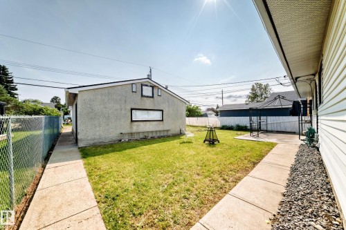 Fenced backyard with a concrete patio, detached garage, and mature lawn - 10819 137 Avenue Nw, Edmonton, AB - Outdoor