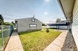 Fenced backyard with a concrete patio, detached garage, and mature lawn - 