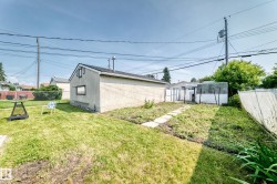 Detached garage with a pitched roof and stucco siding, featuring a small side window - 