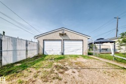 Detached two-car garage with stucco exterior and white garage doors - 