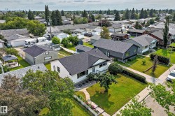 Single-story residence featuring a white exterior, dark shingle roof, and established landscaping - 