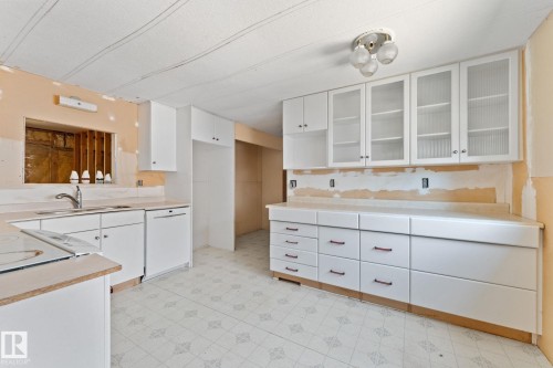 Kitchen featuring white cabinetry, a built-in sink with a chrome faucet, light-colored countertops, and patterned floor tile - 219 Lee Ridge Road, Edmonton, AB - Indoor