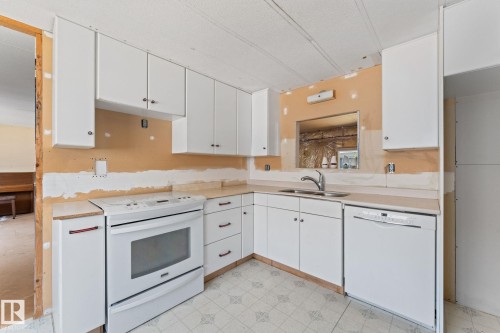 Kitchen featuring white cabinetry, a built-in range, a stainless steel sink with a gooseneck faucet, a built-in dishwasher, and patterned tile flooring - 219 Lee Ridge Road, Edmonton, AB - Indoor Photo Showing Kitchen With Double Sink