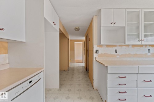 Kitchen featuring white cabinetry with red-toned hardware, light-toned countertops, and a built-in dishwasher - 219 Lee Ridge Road, Edmonton, AB - Indoor Photo Showing Kitchen