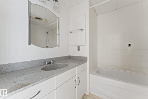 Bathroom featuring a vanity with a built-in sink, an oval mirror, and a bathtub with tiled surround - 219 Lee Ridge Road, Edmonton, AB - Indoor Photo Showing Bathroom