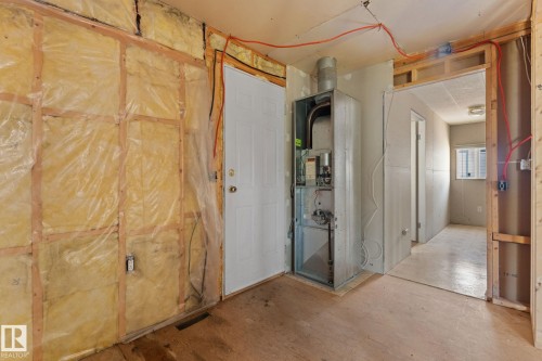 Unfinished interior space featuring exposed insulation, wood framing, a white paneled door, and an exposed HVAC unit - 219 Lee Ridge Road, Edmonton, AB - Indoor Photo Showing Other Room