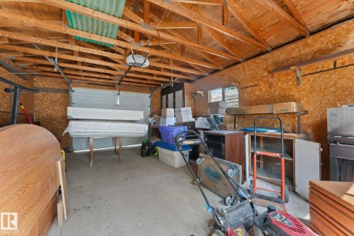 Garage interior with exposed wood beam ceiling, concrete flooring, and an automatic overhead door - 219 Lee Ridge Road, Edmonton, AB - Indoor Photo Showing Garage