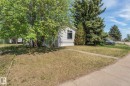 Front exterior featuring white horizontal siding, a single window with dark trim, and mature landscaping including a large flowering tree and evergreens - 219 Lee Ridge Road, Edmonton, AB  - Outdoor 