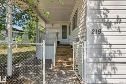 Covered front porch with white siding exterior, chain link fencing, and a concrete pathway leading to the entrance - 219 Lee Ridge Road, Edmonton, AB - Outdoor