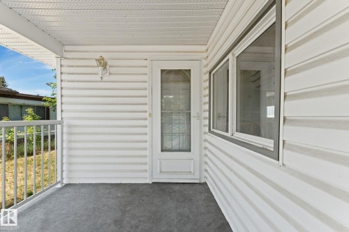 Covered porch featuring a screened entry door, dual-pane windows, white siding, a textured ceiling, and a metal railing - 219 Lee Ridge Road, Edmonton, AB - Outdoor With Exterior